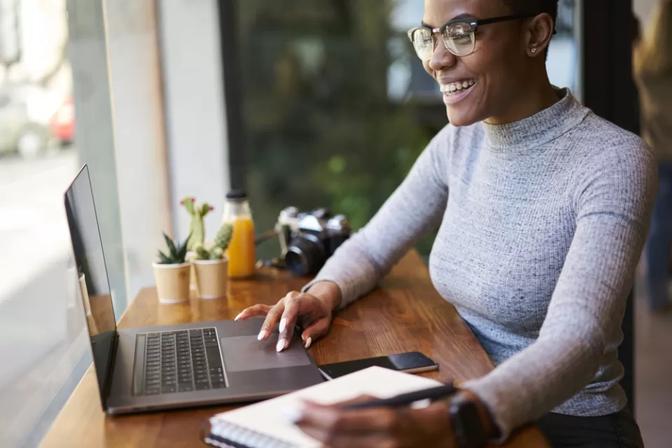 Woman sitting at countertop with laptop facing window